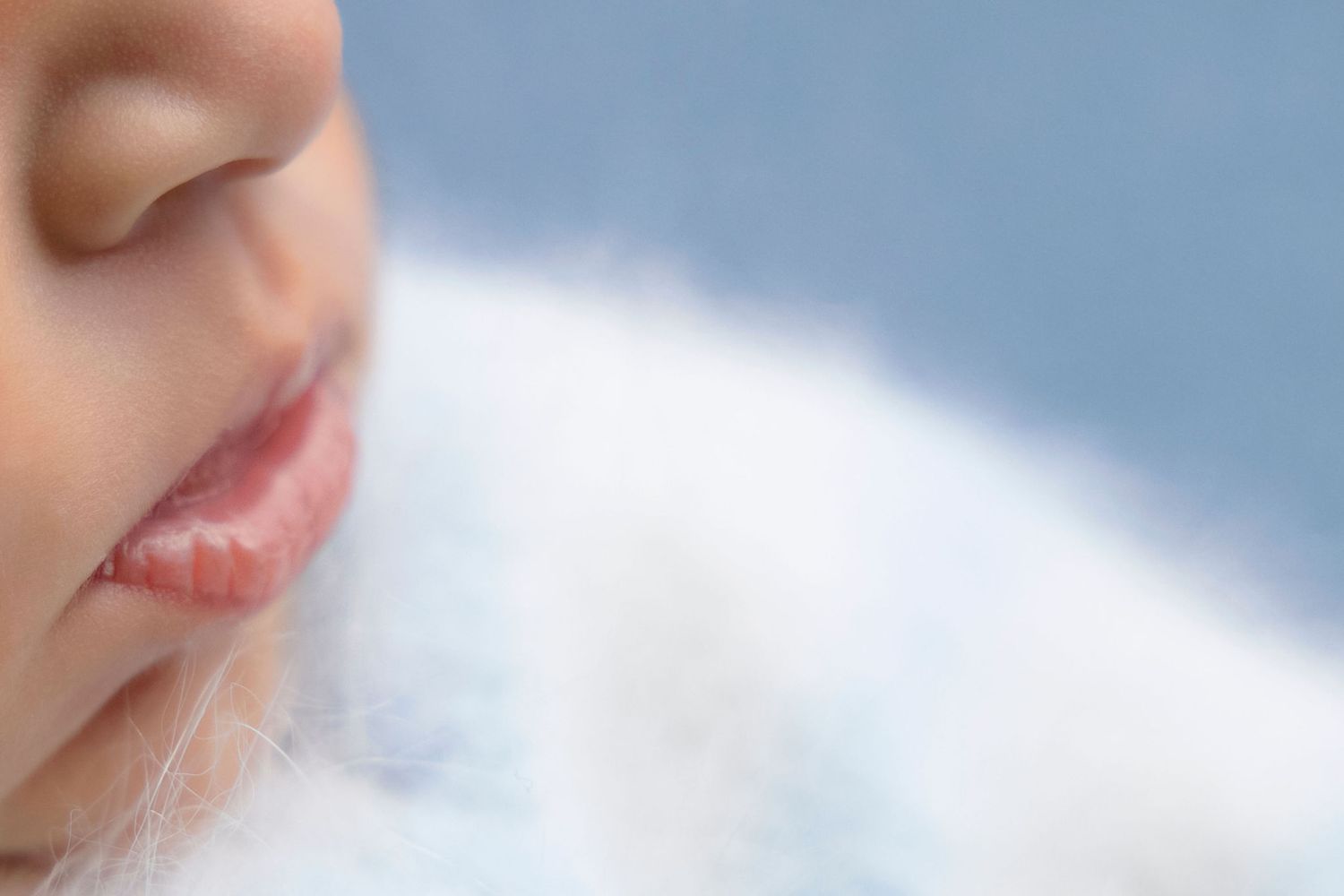 Extreme close-up portrait showing lips and nose against soft white background.