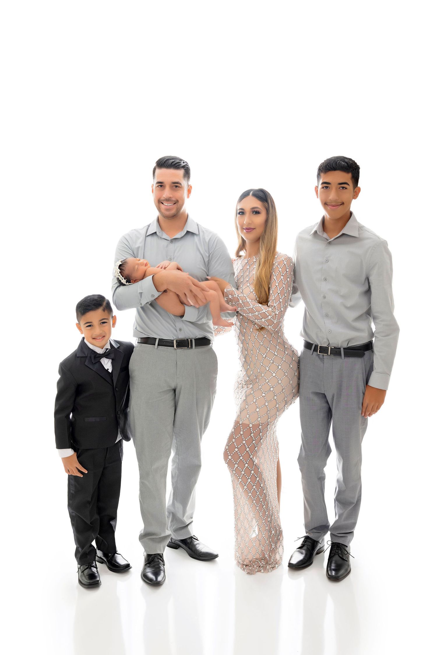 Elegant family portrait with coordinated outfits against white background.