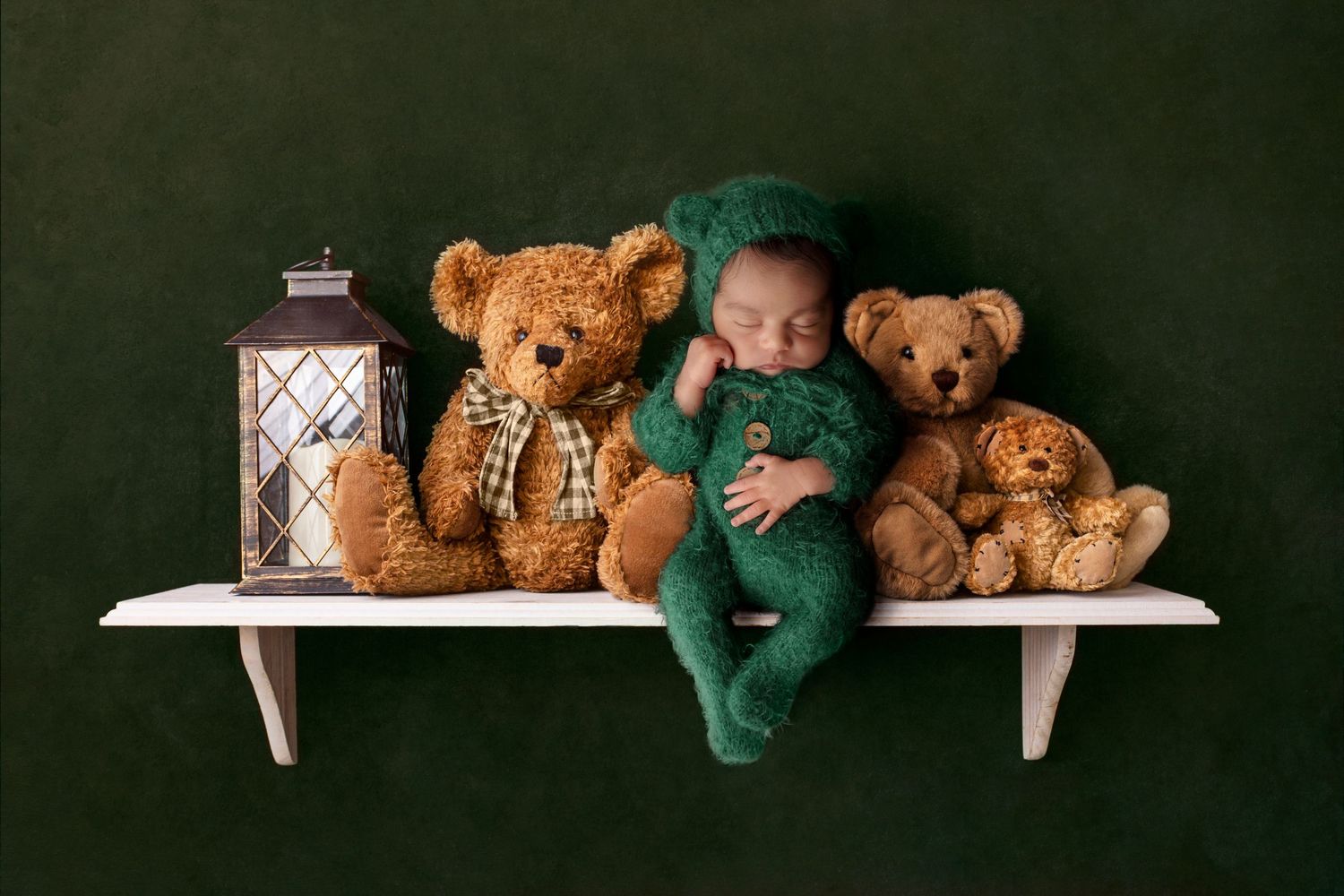 Baby in green outfit sleeping on shelf with teddy bears and vintage lantern.