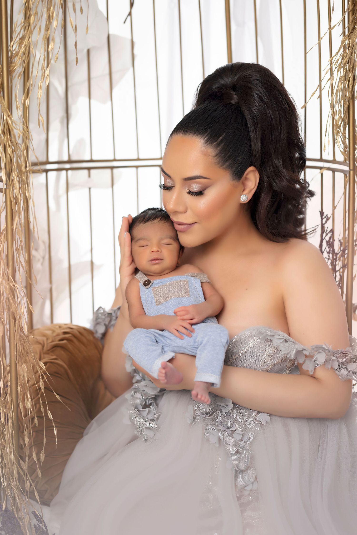 Intimate portrait of mother and baby in elegant gray dress against natural backdrop.