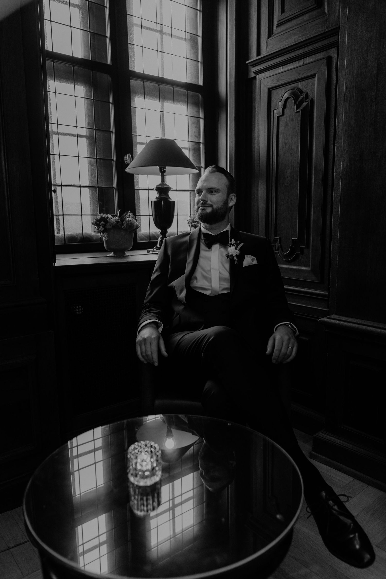 Bräutigam posiert in Smoking in historischer Kulisse während des Paarshootings.