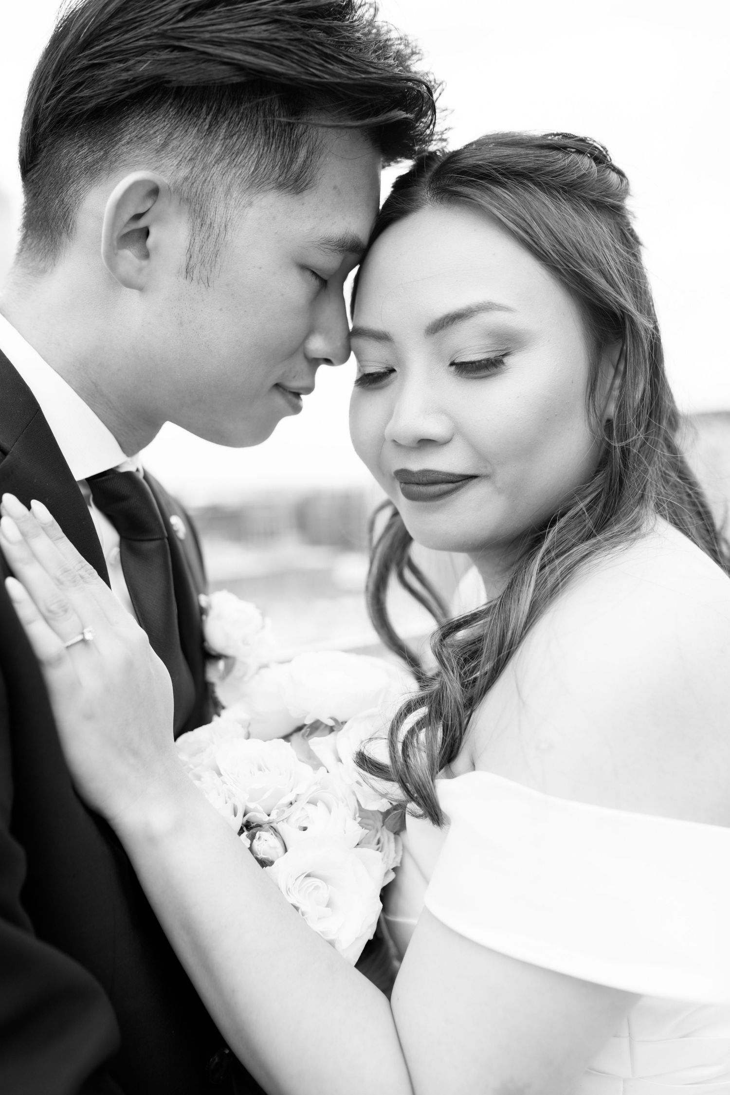 An intimate black and white portrait of a couple in wedding attire.
