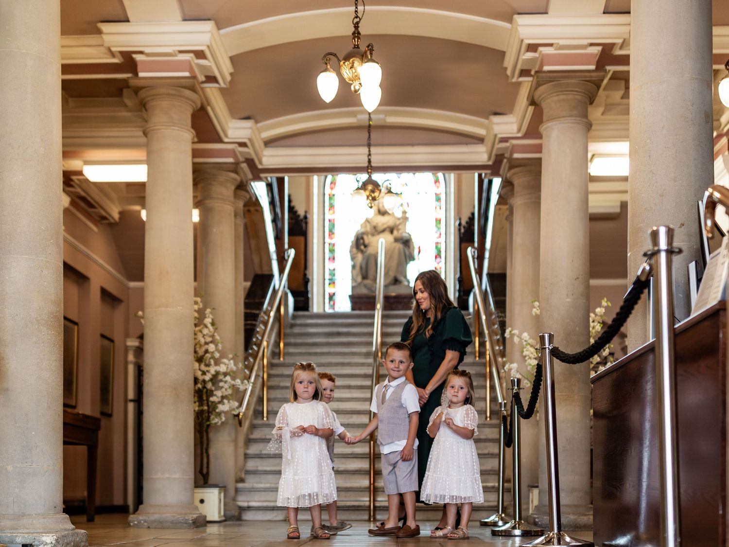 A grand staircase decorated with floral arrangements and columns in an elegant building interior.