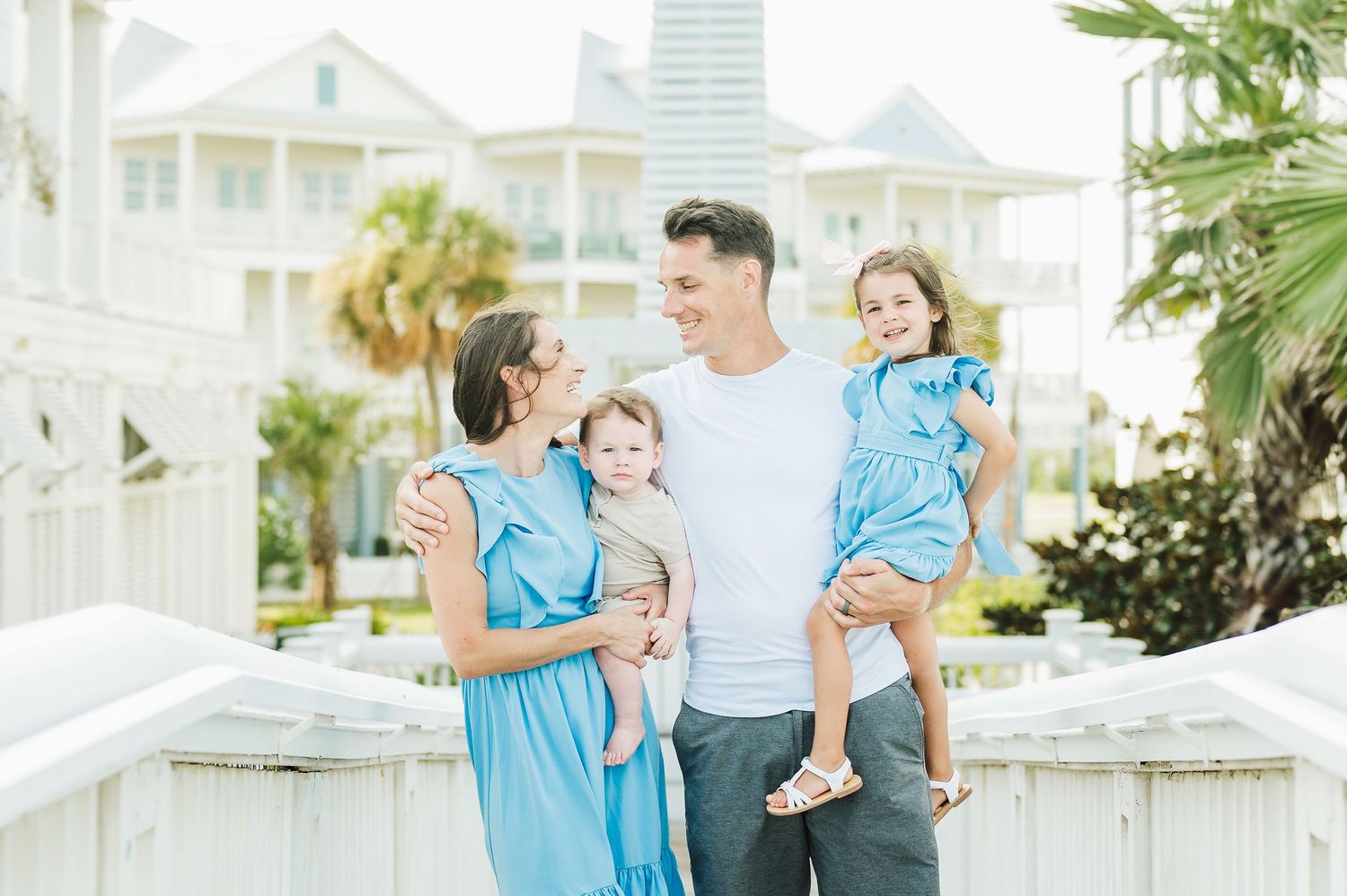 Family portrait session on white coastal boardwalk with toddler.