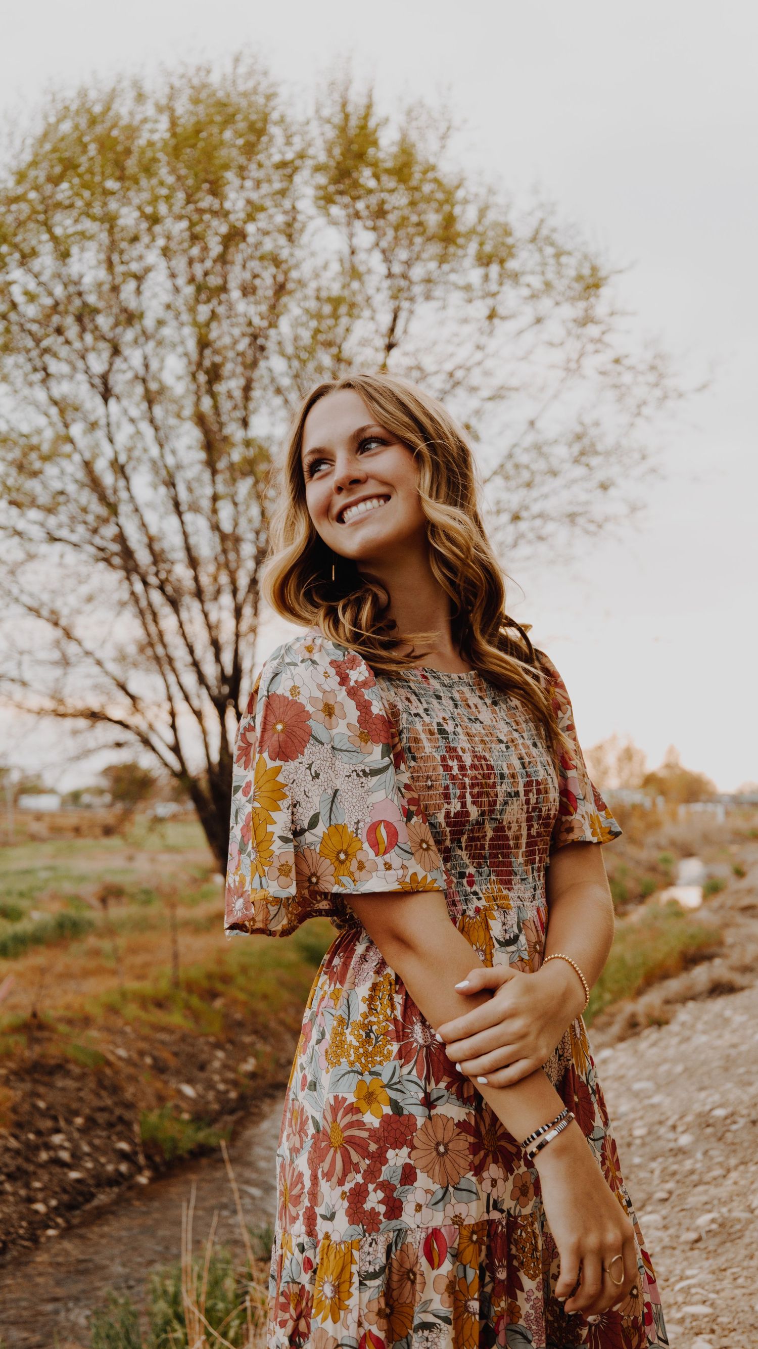 A portrait of a person smiling, captured in natural light, with a simple background.