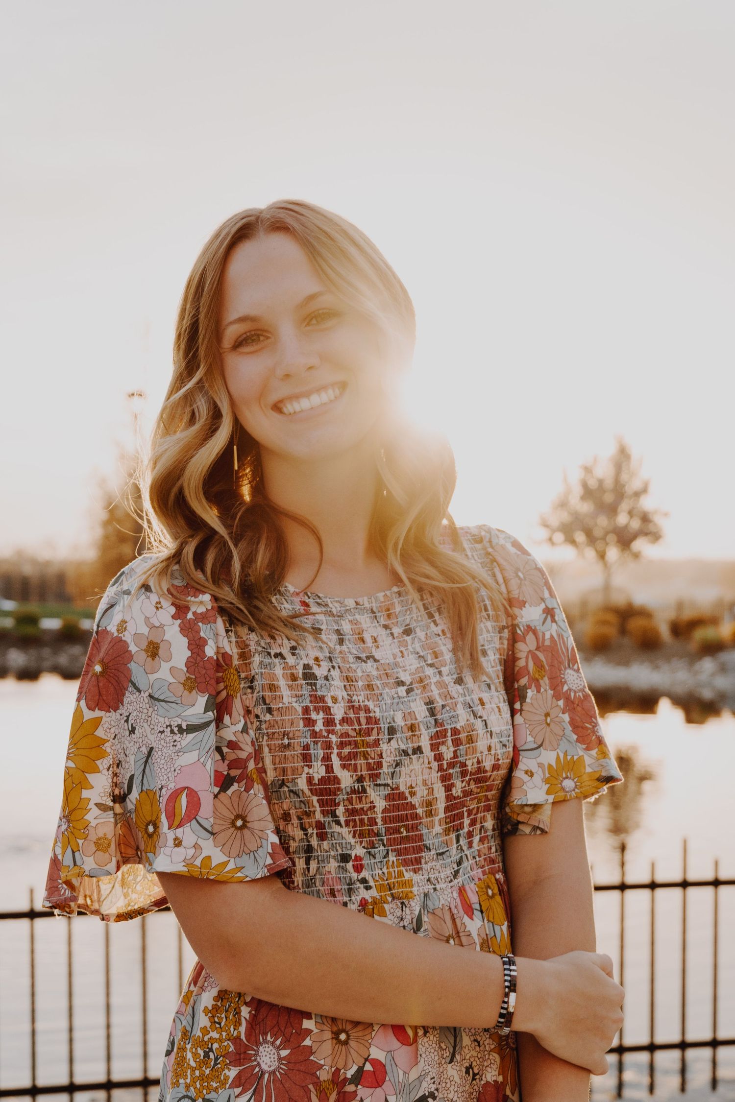 A portrait of a person smiling, captured in natural light, with a simple background.