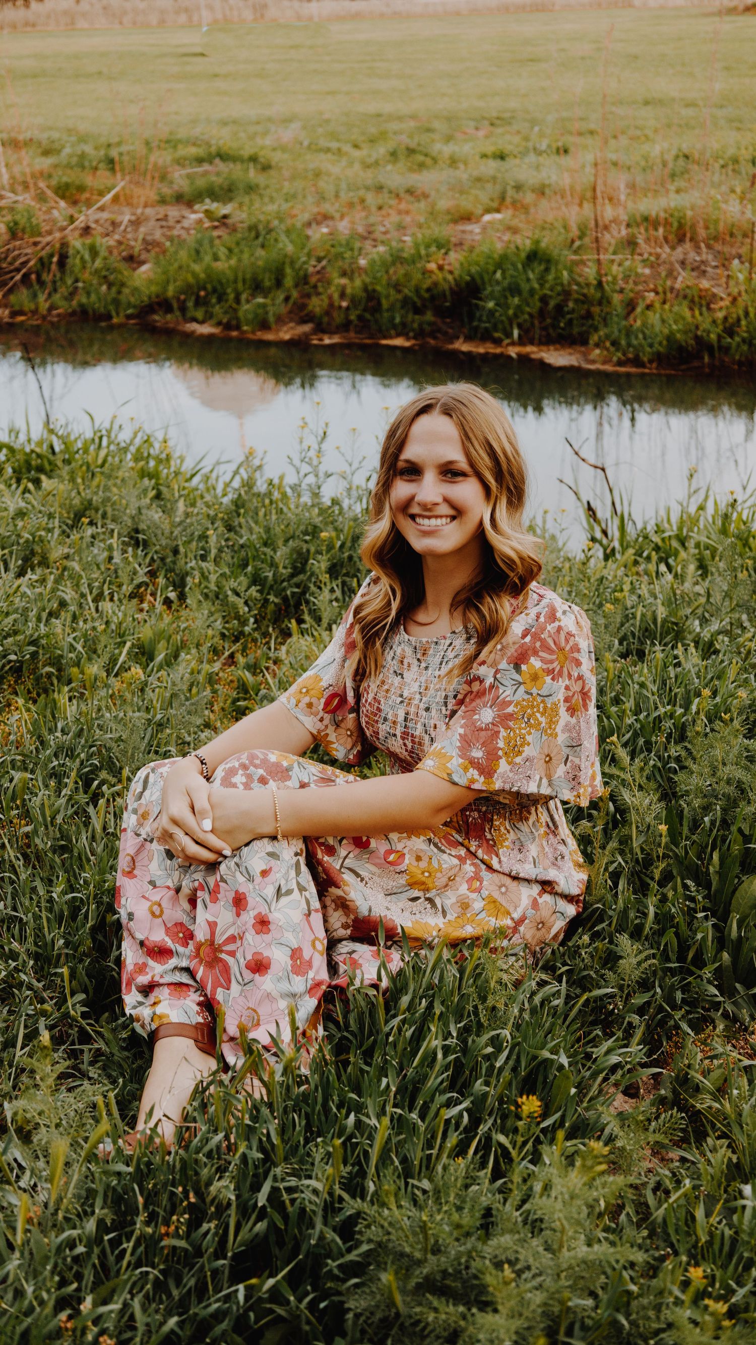 A portrait of a person smiling, captured in natural light, with a simple background.