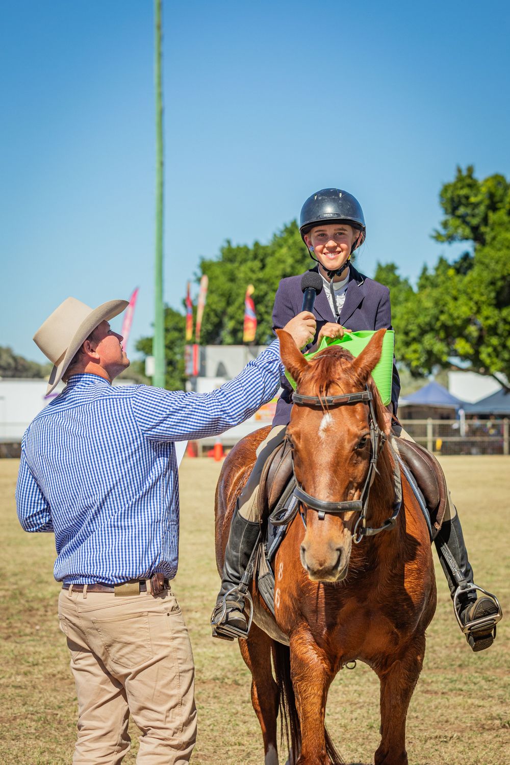 Equestrian rider receives instruction from trainer during outdoor horse event.