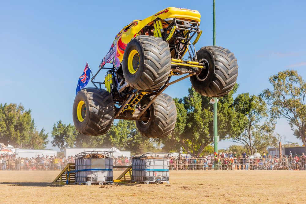 Monster truck performing aerial jump at outdoor motorsport event.
