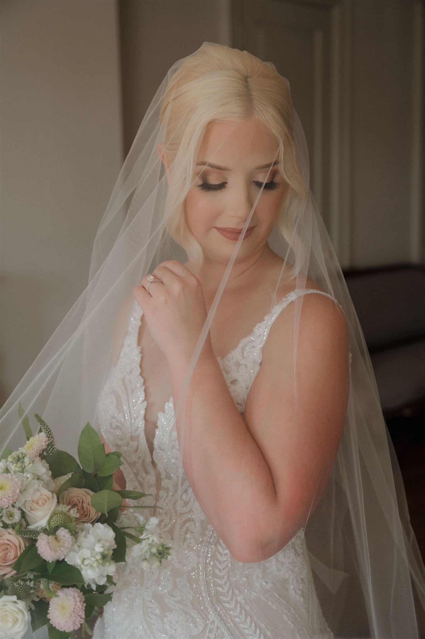 Romantic bridal portrait with soft veil and delicate white and pink bouquet.
