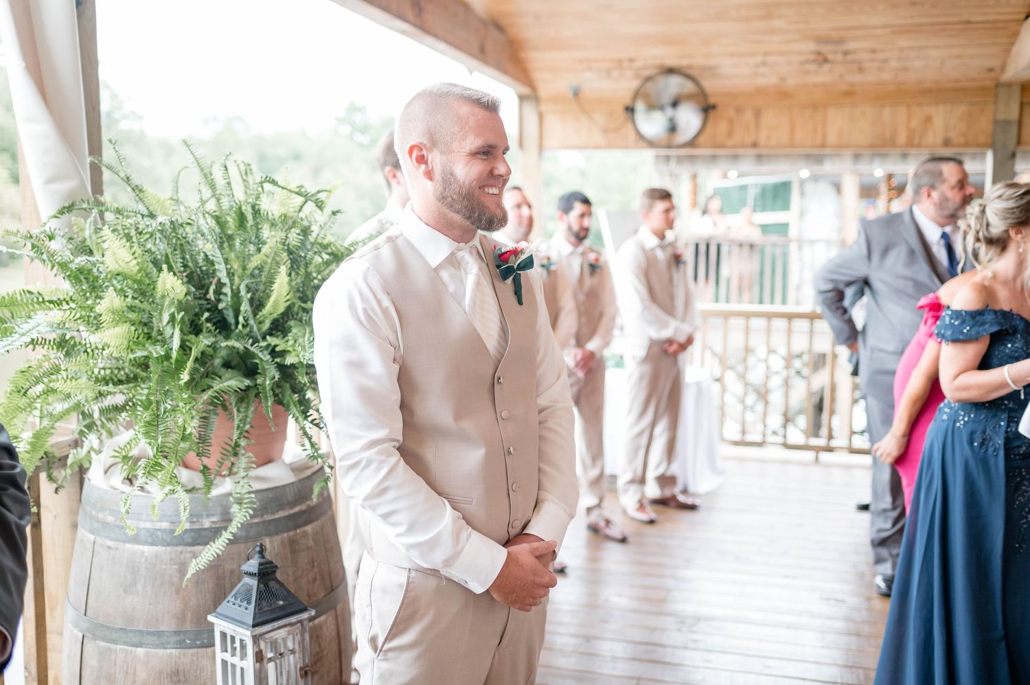 groom smiling while bride walks down the aisle