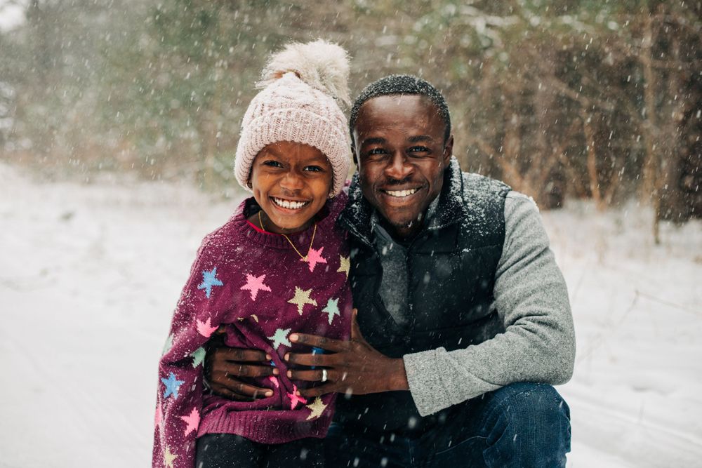 father and child smile in snow