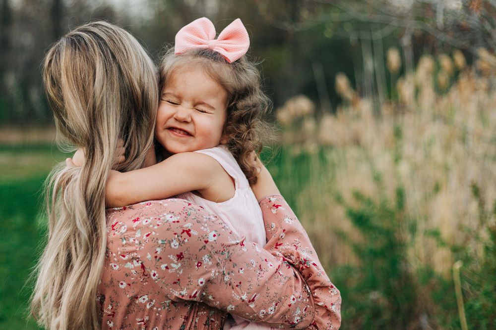 child smiles in woman's arms