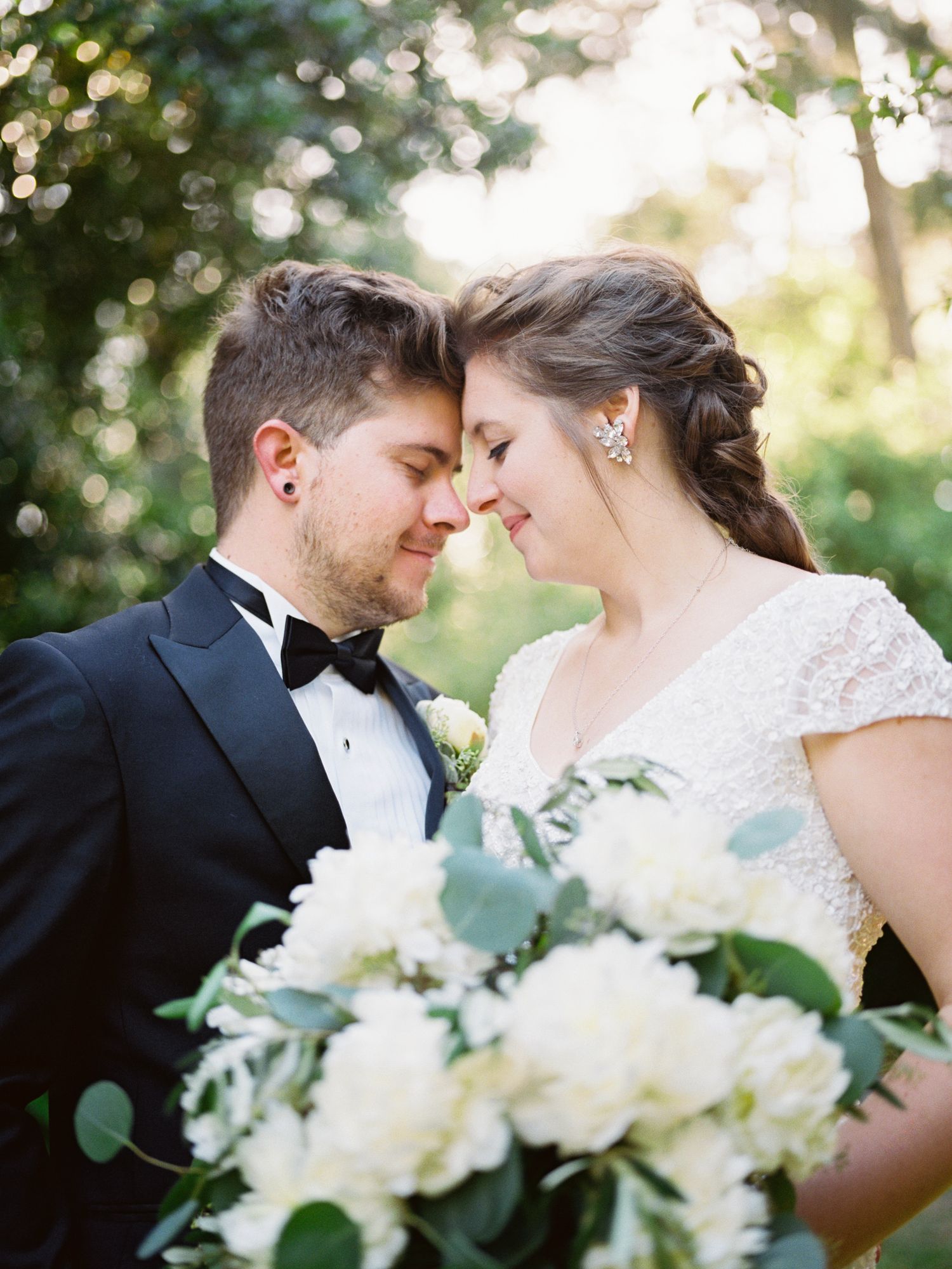 A romantic wedding moment with white bouquet of flowers in a garden setting.