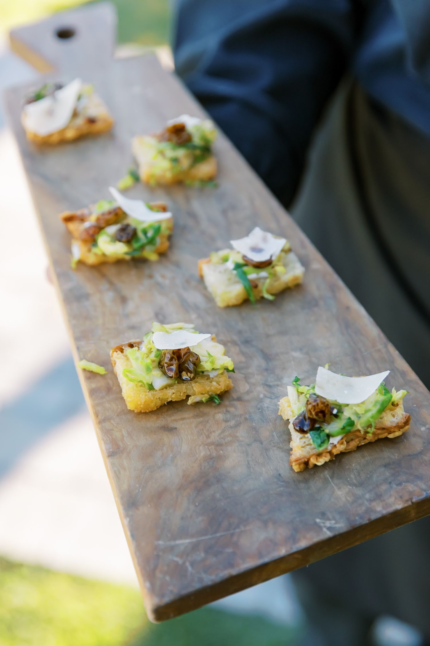 Gourmet appetizers served on wooden board featuring avocado and microgreens.