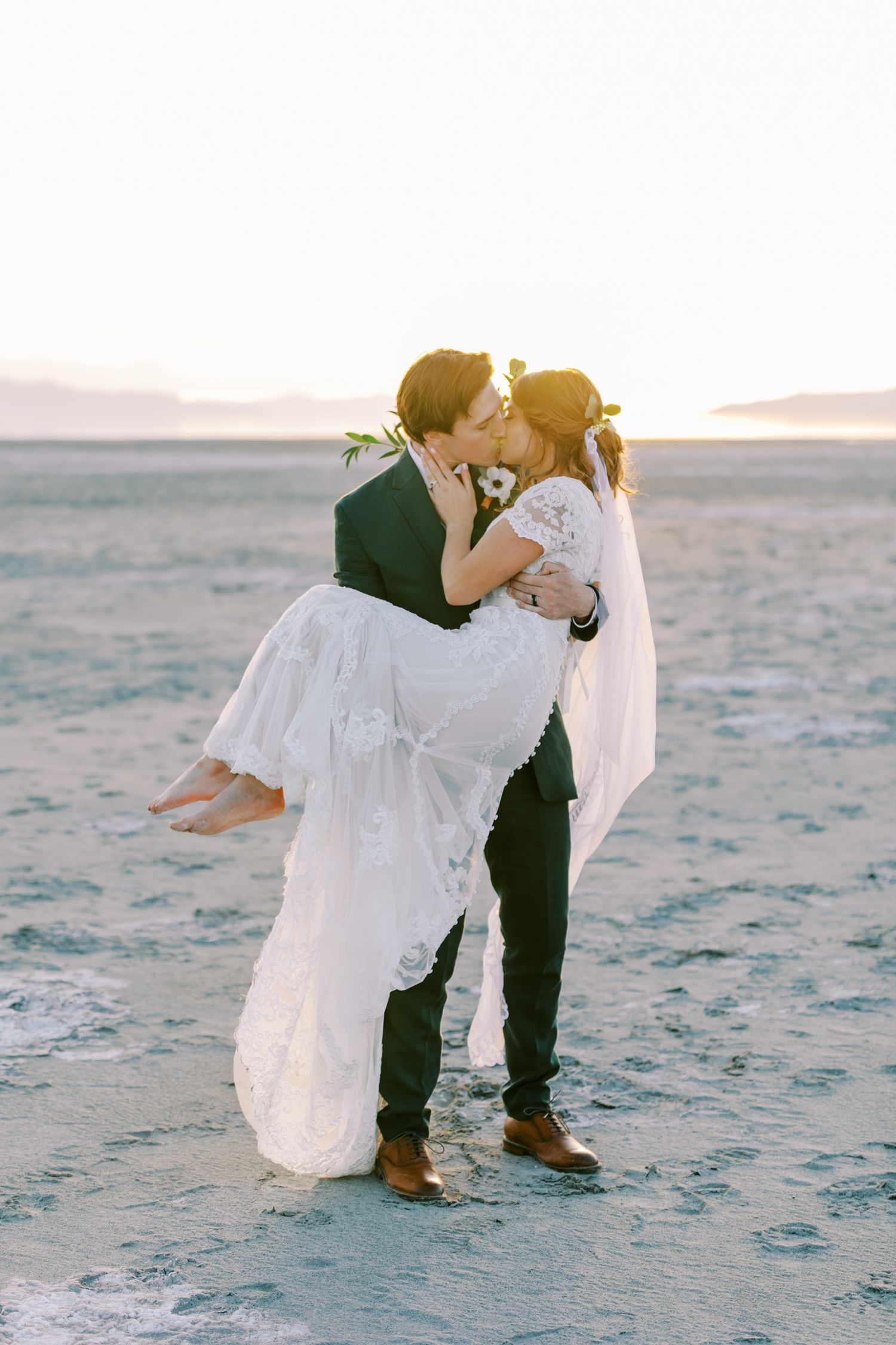 Romantic desert wedding photo of couple embracing at sunset.
