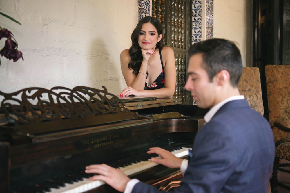 girl looking at a boy playing a piano during the engagement session