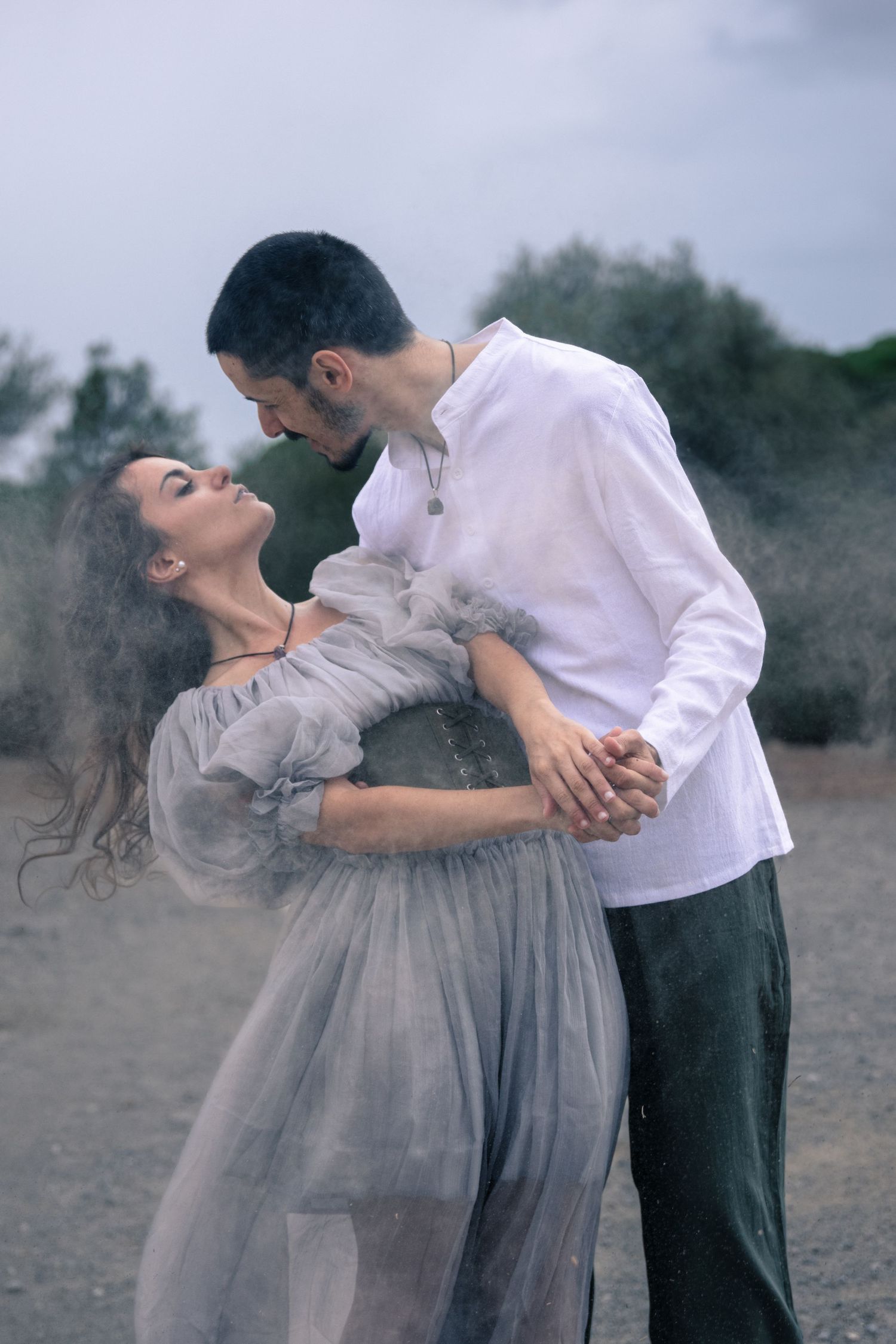 A dreamy maternity photo session with a flowing gray dress against a moody outdoor backdrop.