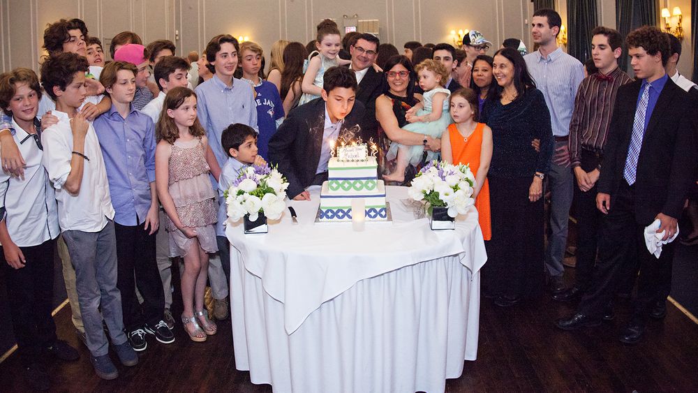 A celebration gathering around a white-clothed table with a cake.