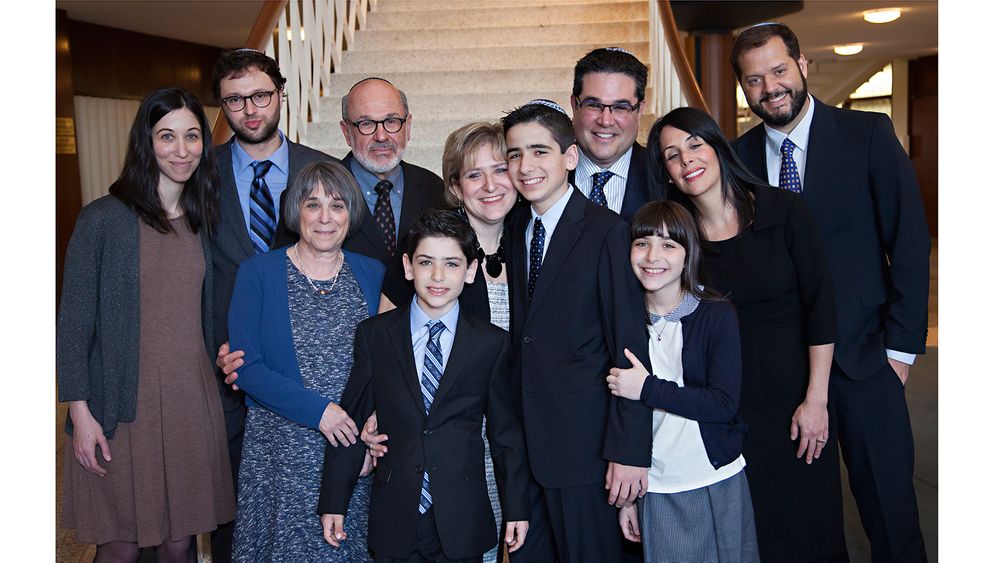A group photo taken indoors near a staircase with formal attire.