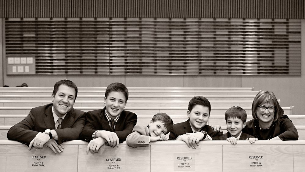 Black and white photo of people lined up along a railing with horizontal lines pattern behind them.