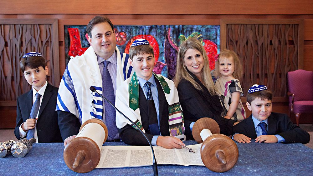 People gathered around a Torah scroll during a religious ceremony.