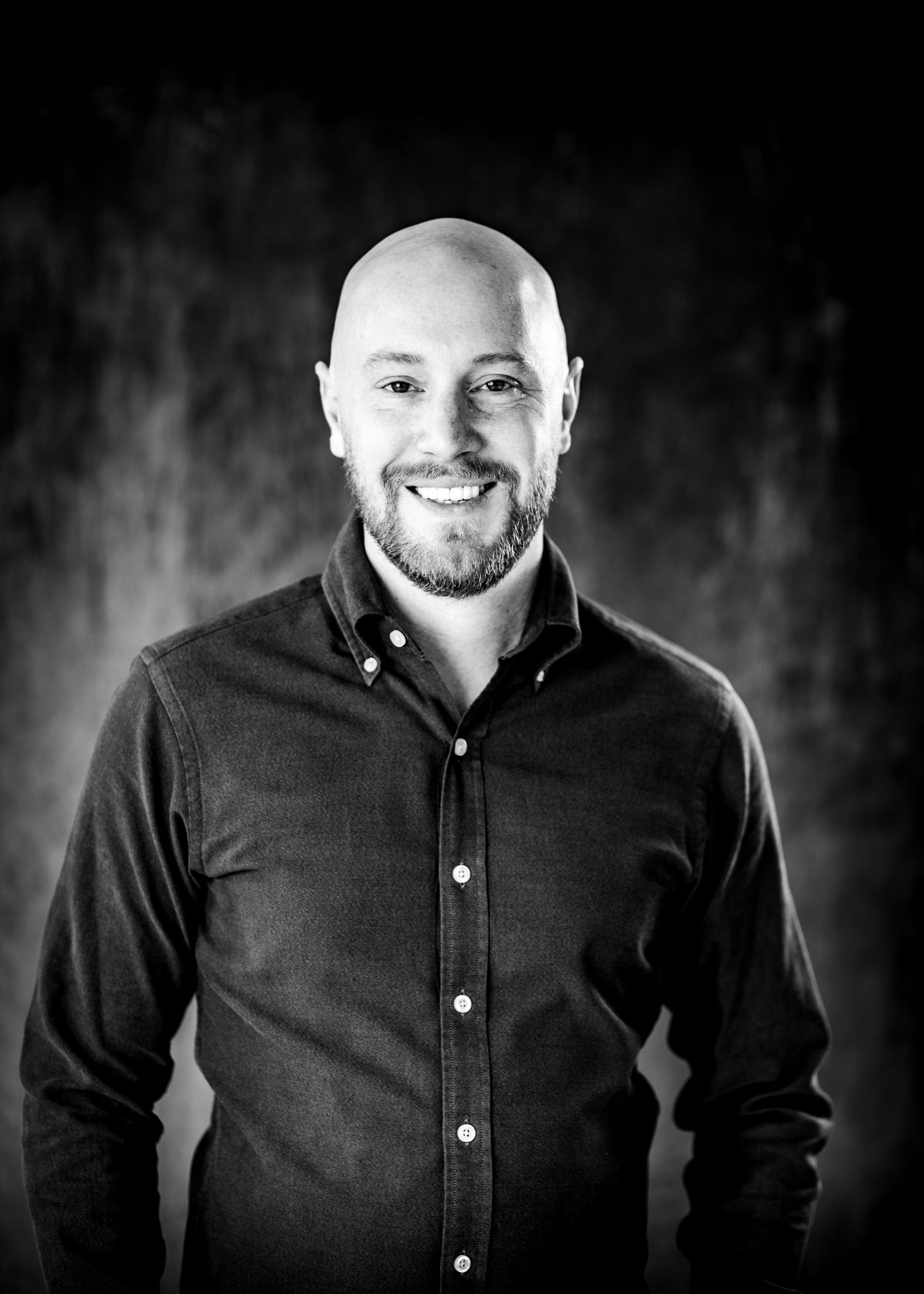 Black and white headshot of a person in a button-down shirt with a cheerful expression.