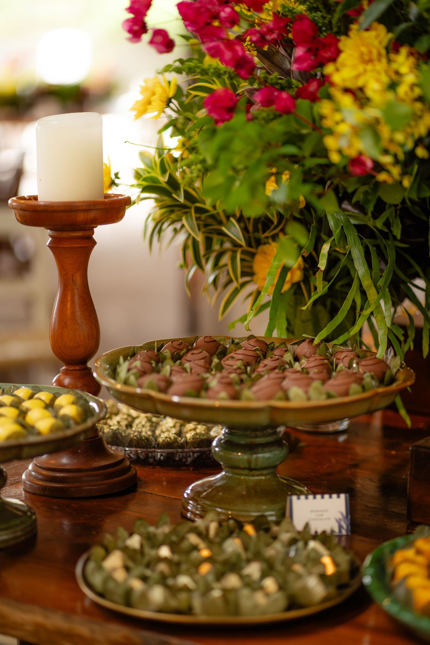 Dessert table with candlesticks and appetizer platters decorated with bright floral arrangements.