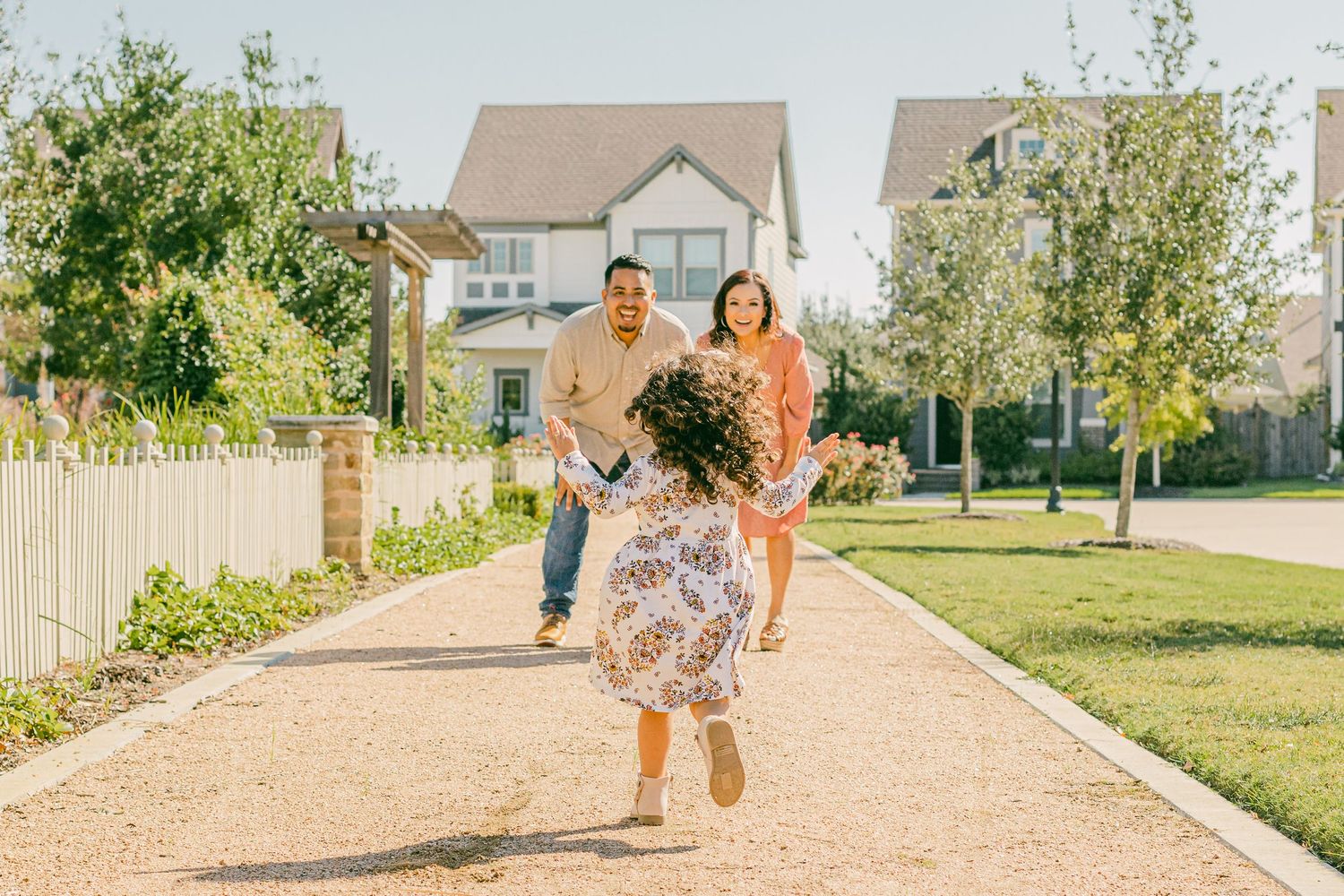 a little girl runs towards her smiling parents with outstretched arms