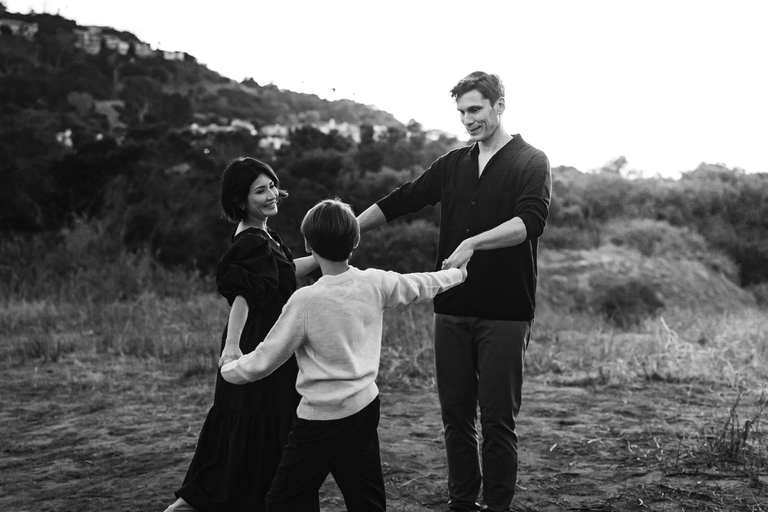 Black and white family moment captured outdoors at dusk.