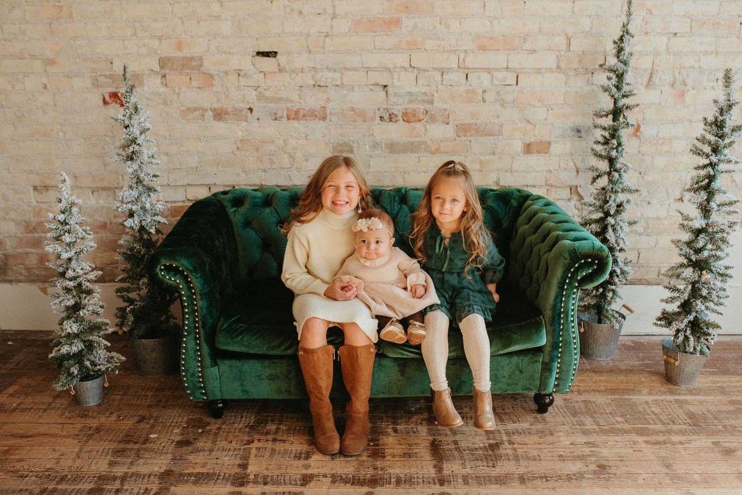 Family sitting together on emerald green velvet couch with holiday decorations.