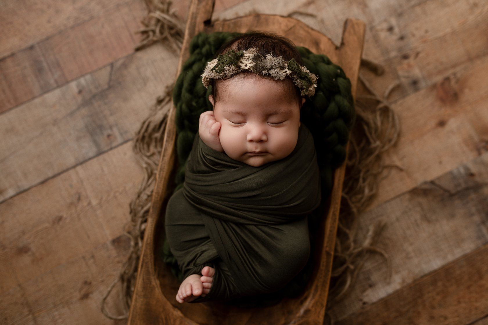 Eden Prairie newborn photographer | Newborn-baby-wrapped-in-green-cloth-with-headband-in-wooden-bowl-on-wood-floor