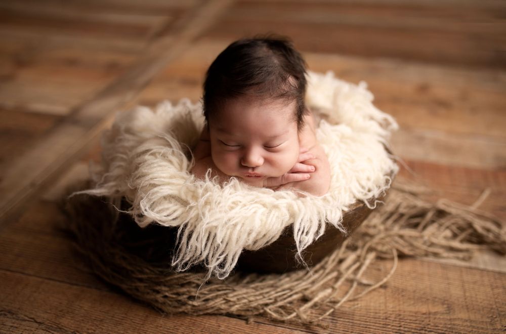 Eden Prairie newborn photographer | Newborn-baby-on-a-cream-layer-in-a-wooden-bowl-on-top-of-jute-layer-on-wood-floor