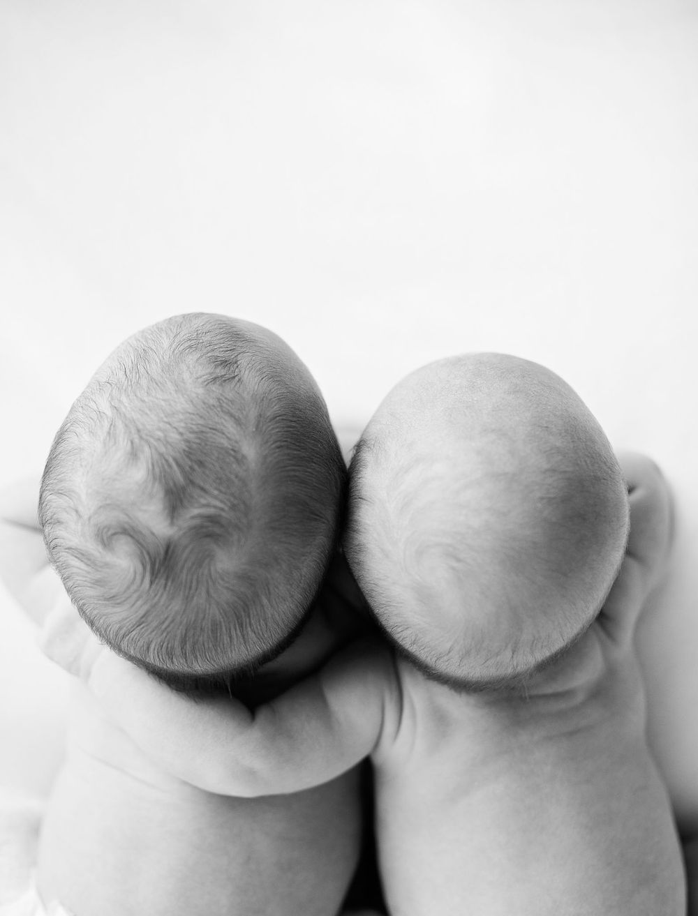 eden prairie newborn photographer | black-and-white-image-of-two-twin-babies-laying-with-one-arm-around-the-other