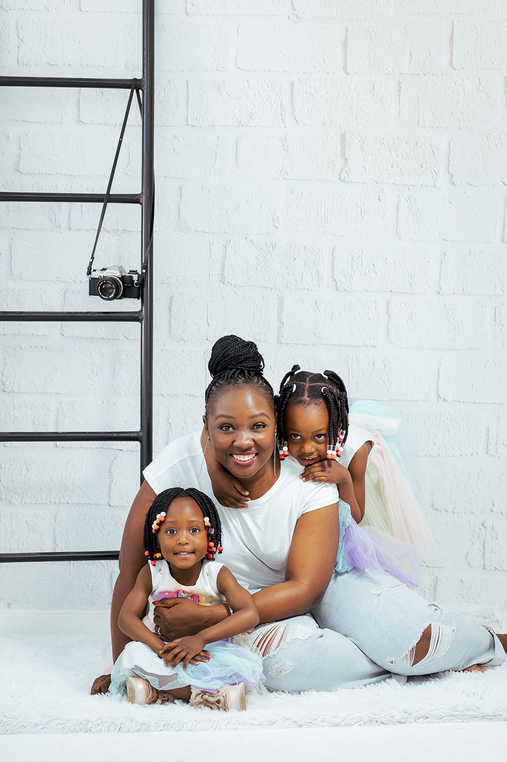 Joyful family poses together on white fur rug with ladder prop.