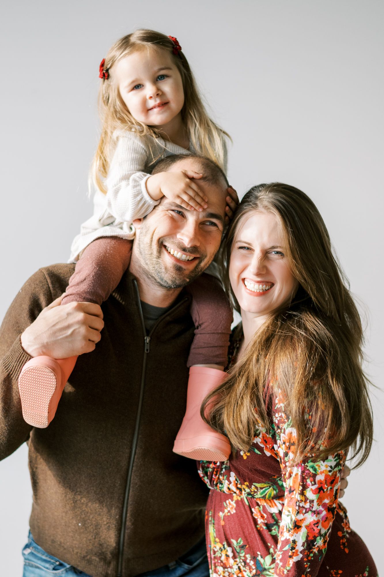 A joyful family portrait against a white background in casual attire.