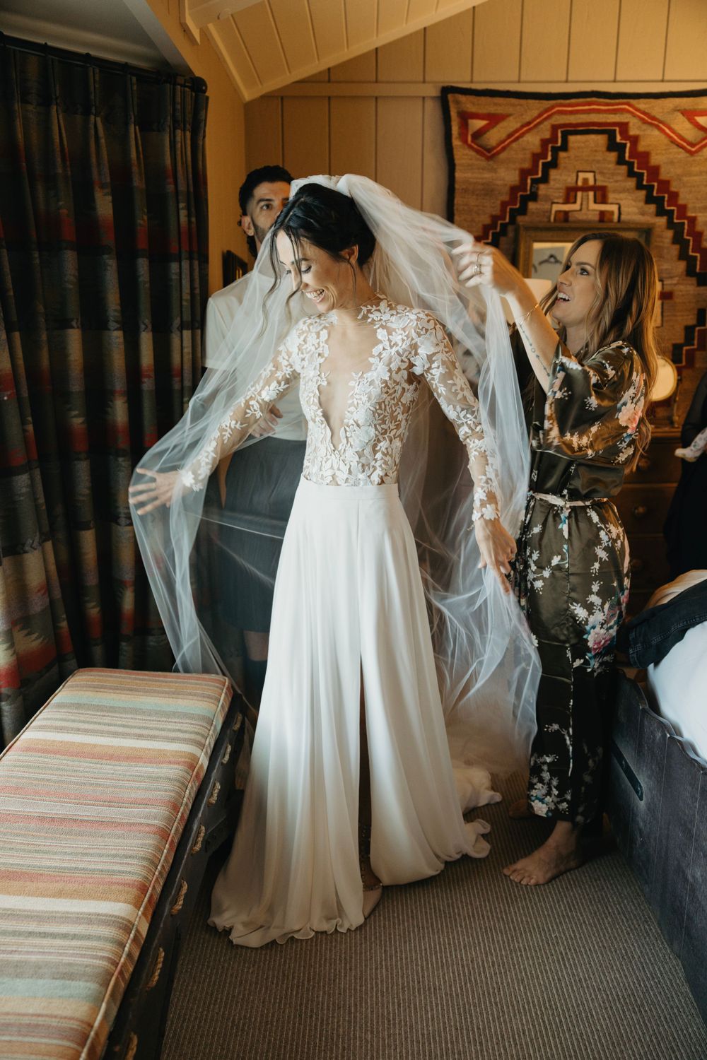 Wedding dress with flowing veil captured in warm-toned room with striped furnishings.