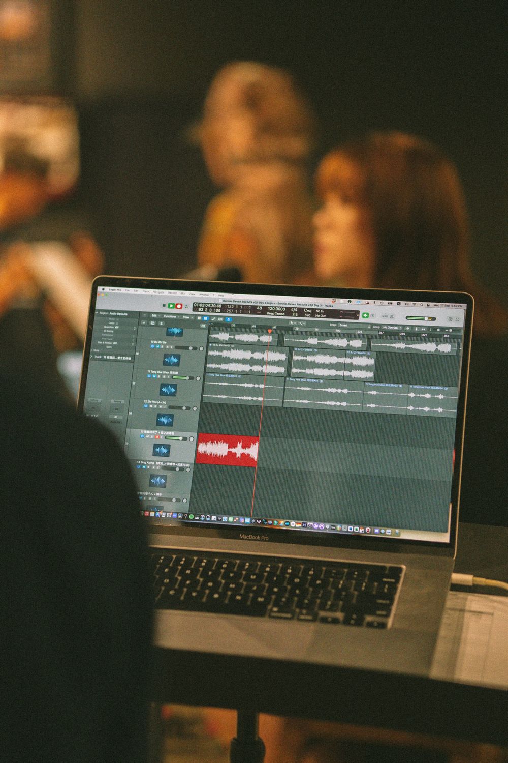 Audio production software displayed on laptop screen in recording studio environment.