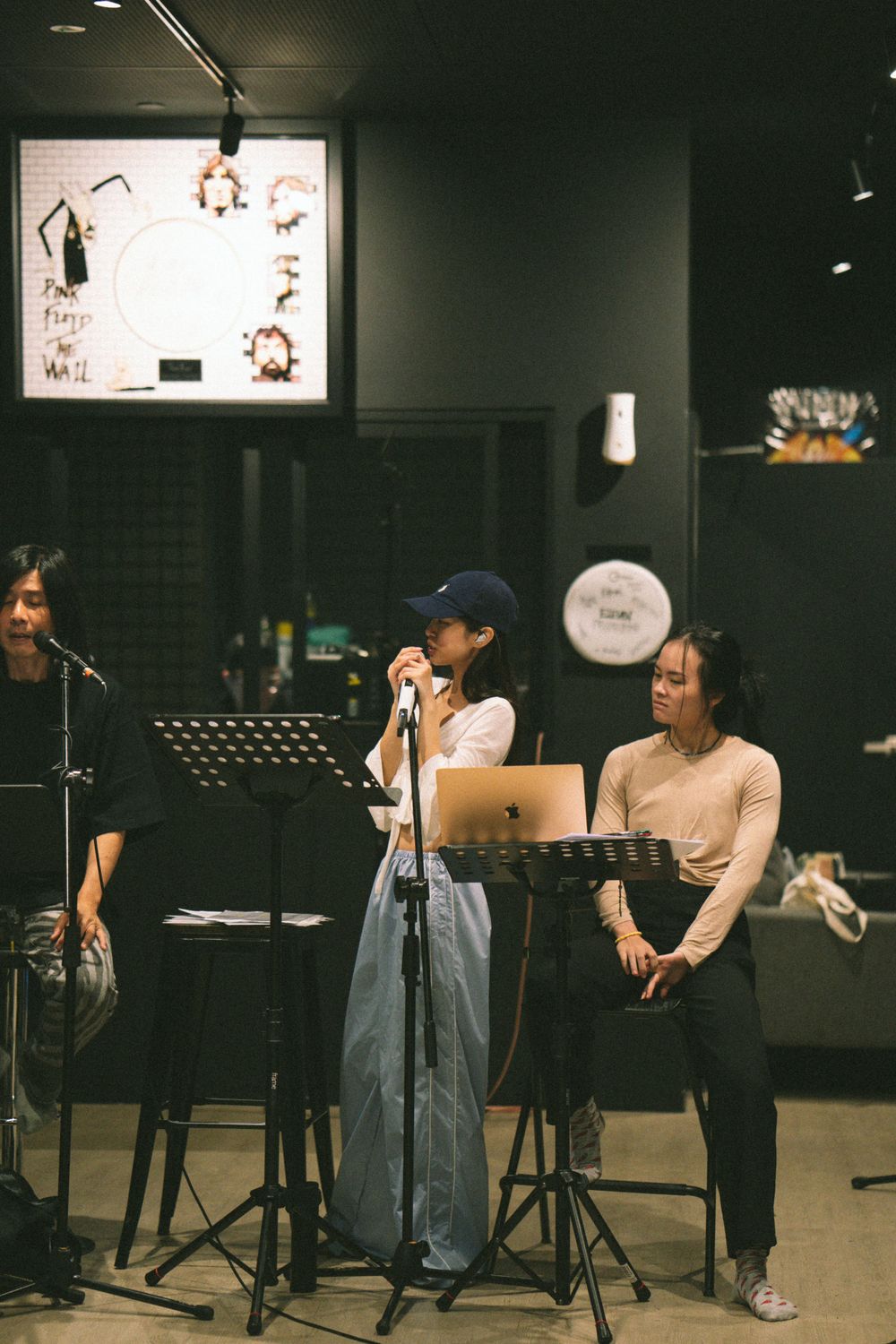 Musicians rehearse with microphones and music stands in a studio space.