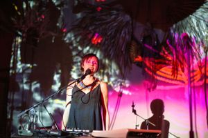 Concert stage setup with palm trees and red lighting creating a tropical nightclub ambiance.