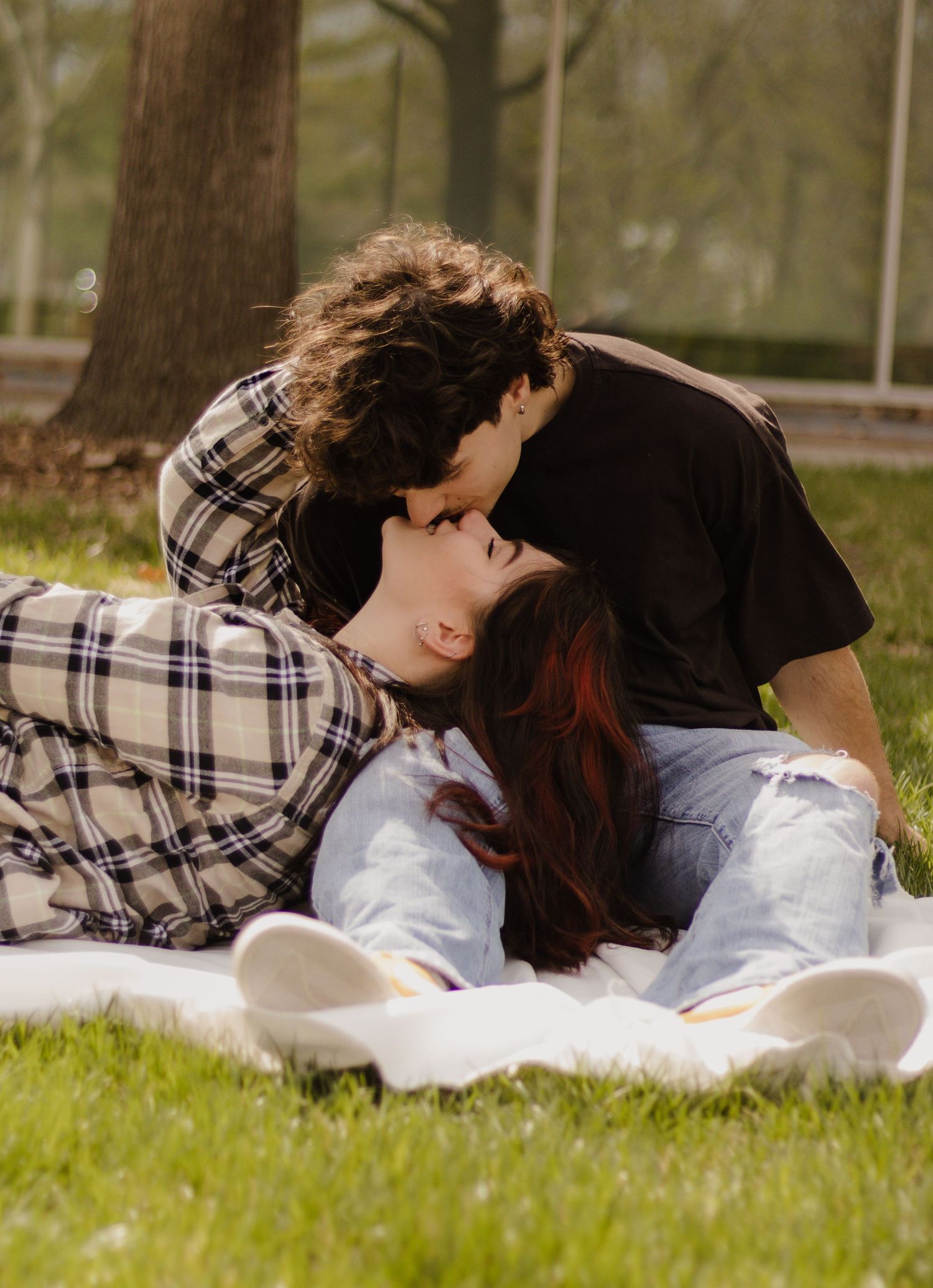 Couple sharing an intimate moment while lying on grass in a park.