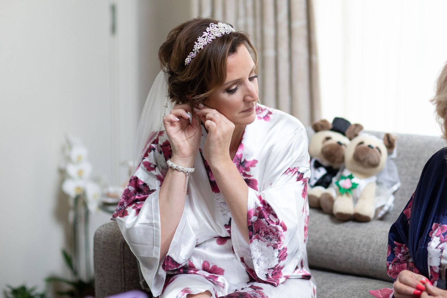 Bride putting in her earrings on the morning of her wedding, wearing a bridal crown