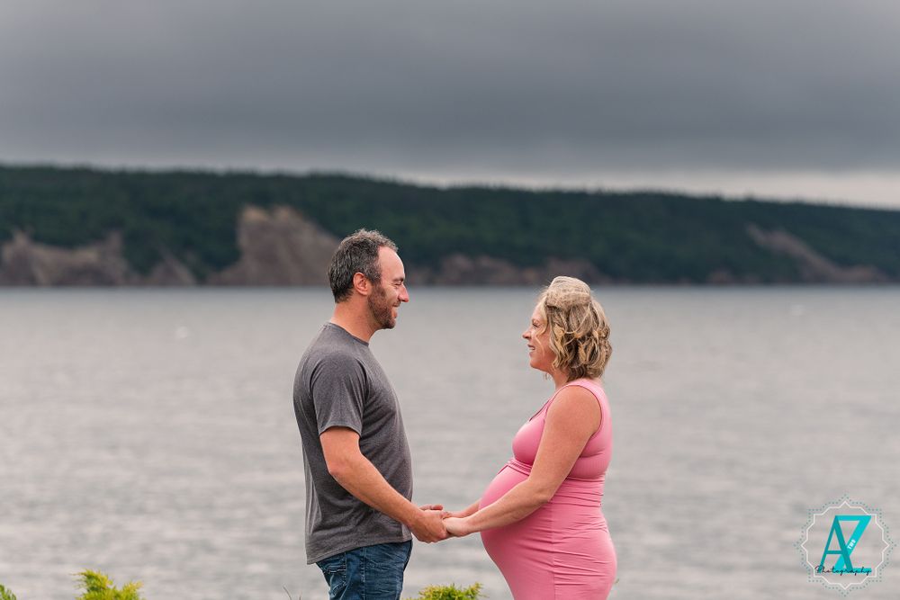 Maternity photo session by scenic coastal cliffs on overcast day.