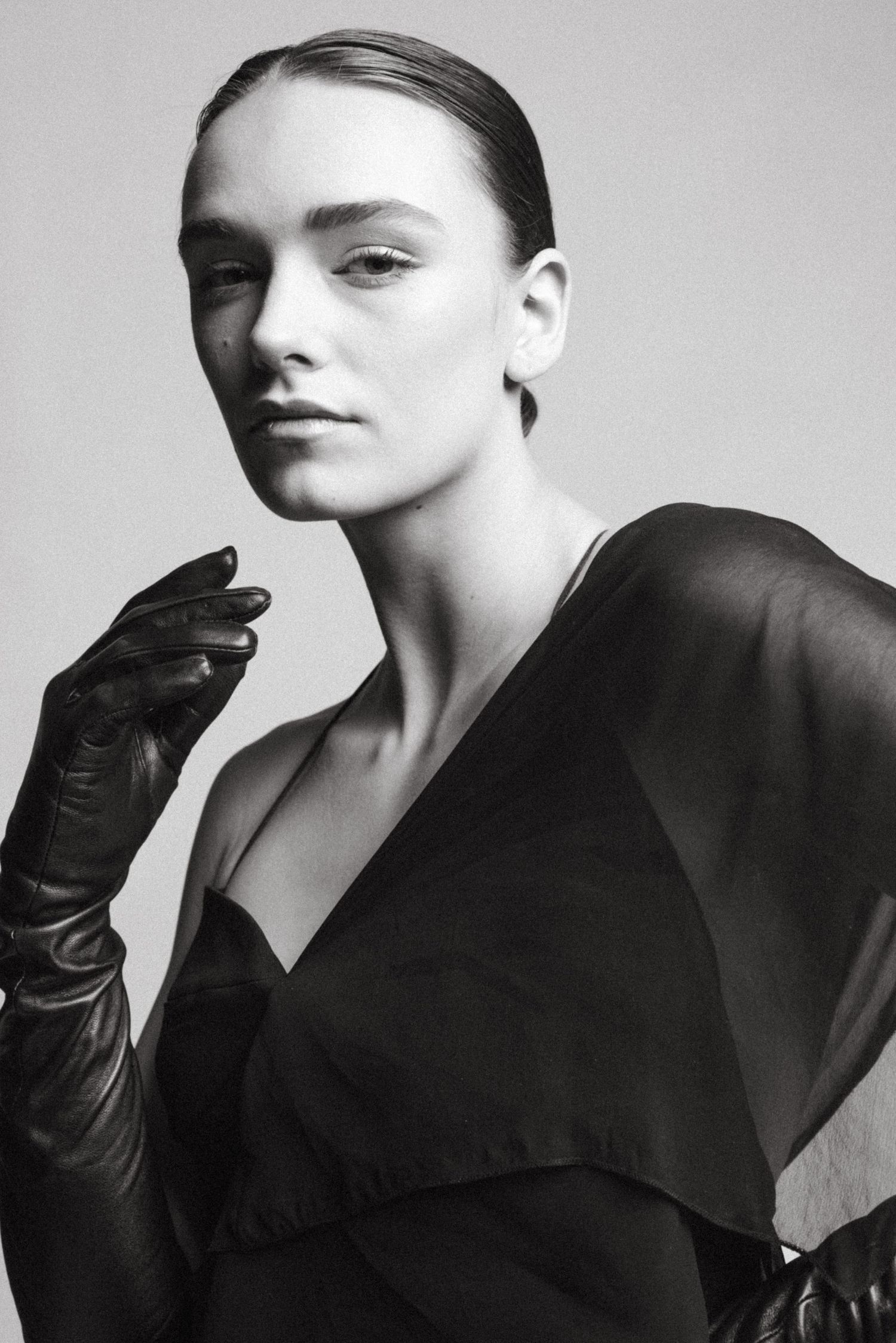 Dramatic black and white portrait of a model wearing long gloves and elegant black clothing.
