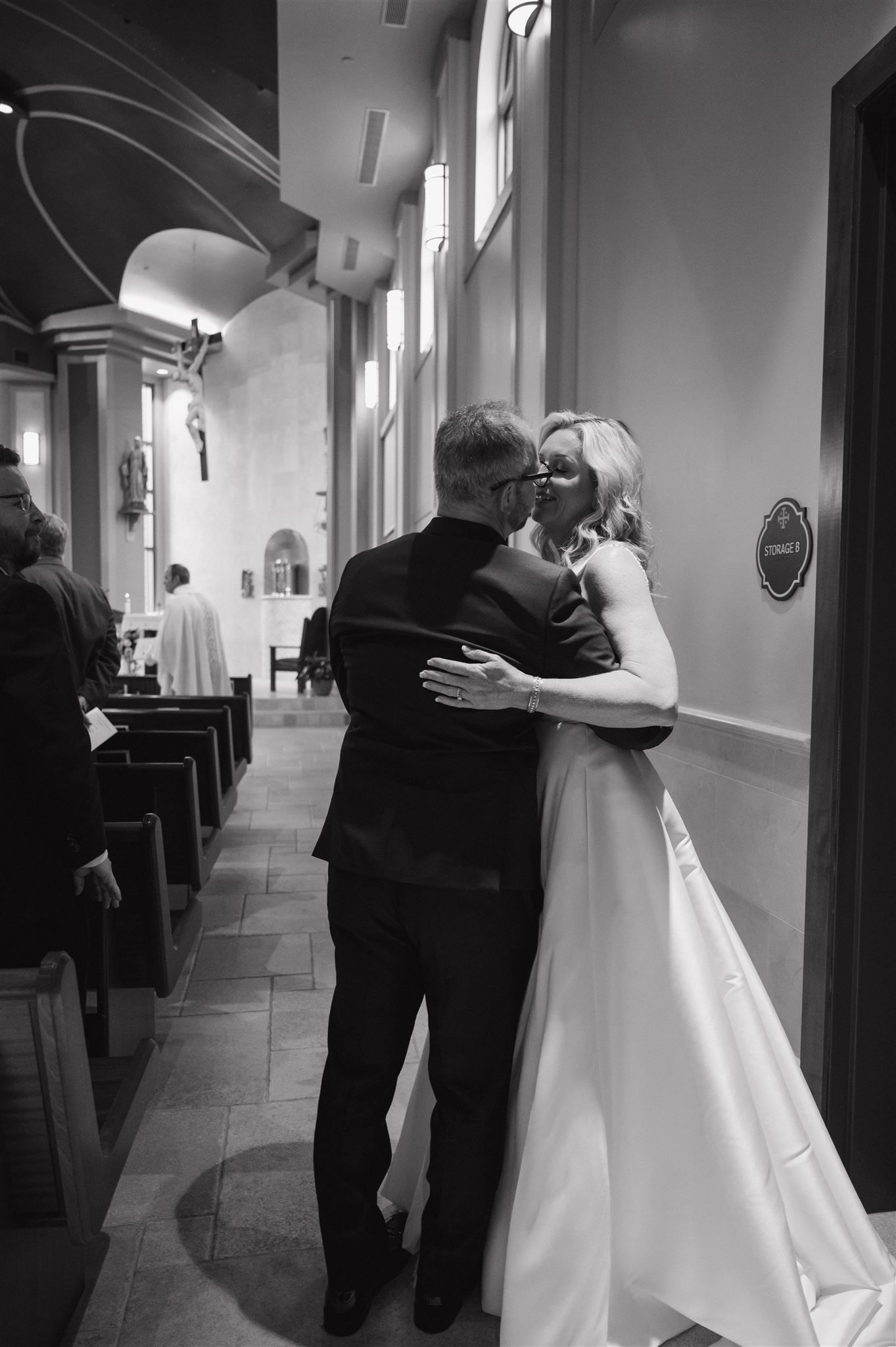 A tender embrace in a church hallway captured in black and white photography.