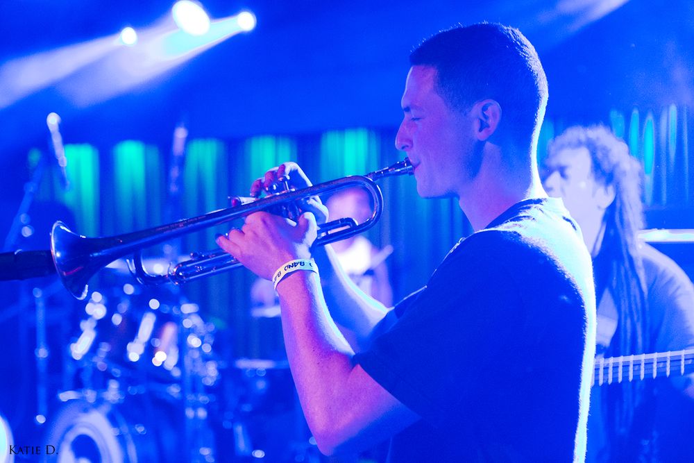 Trumpet player performing on stage bathed in blue concert lighting.