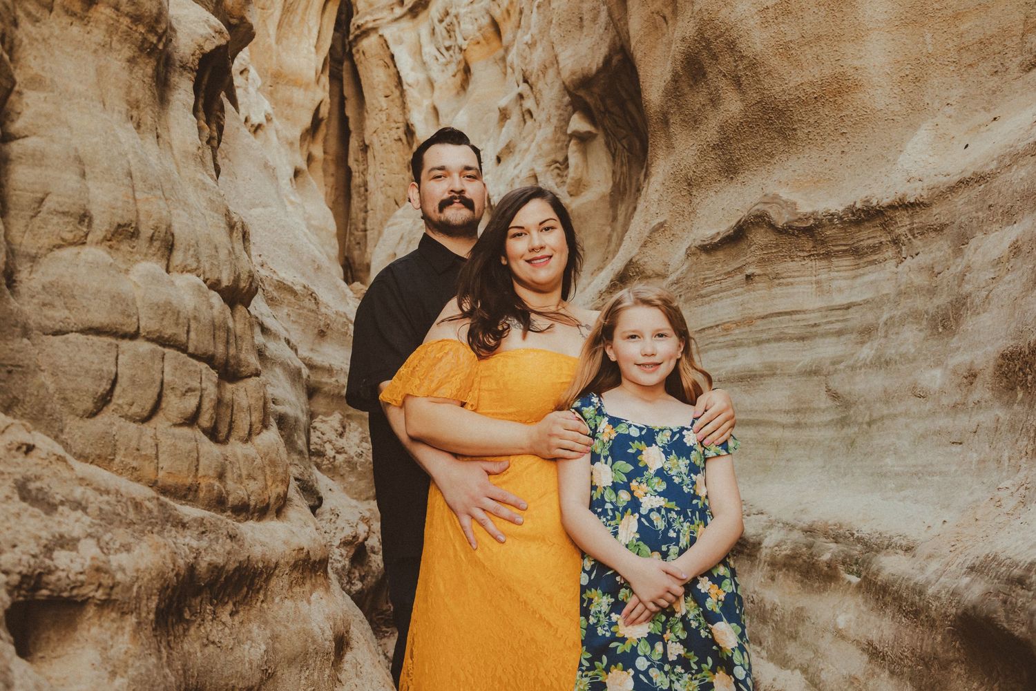 Family portrait taken in front of textured sandstone canyon walls.