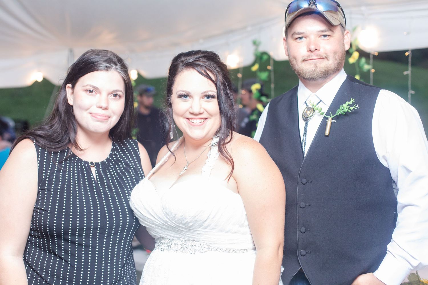 Wedding reception guests gathered under tent celebrating the newlyweds.