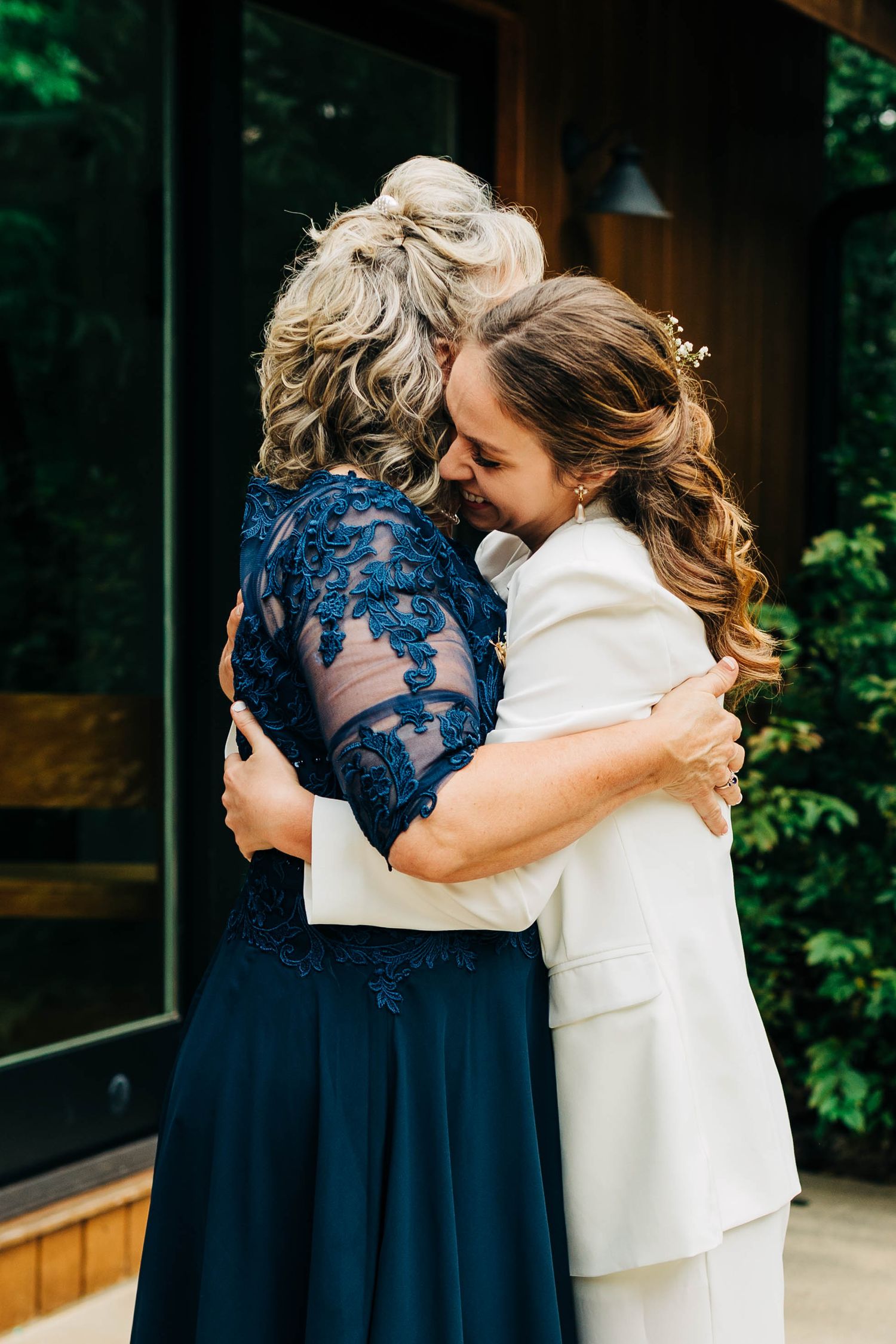 Emotional embrace between two people wearing white and navy blue formal attire.