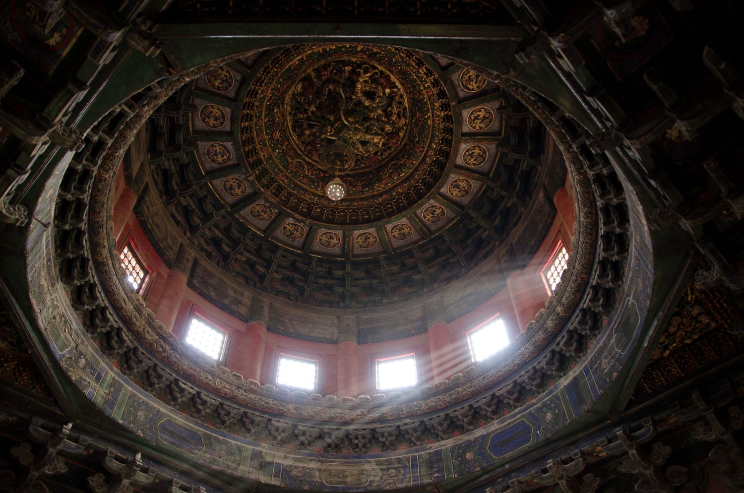 Ornate baroque dome interior with circular windows letting in natural light and detailed religious frescoes.